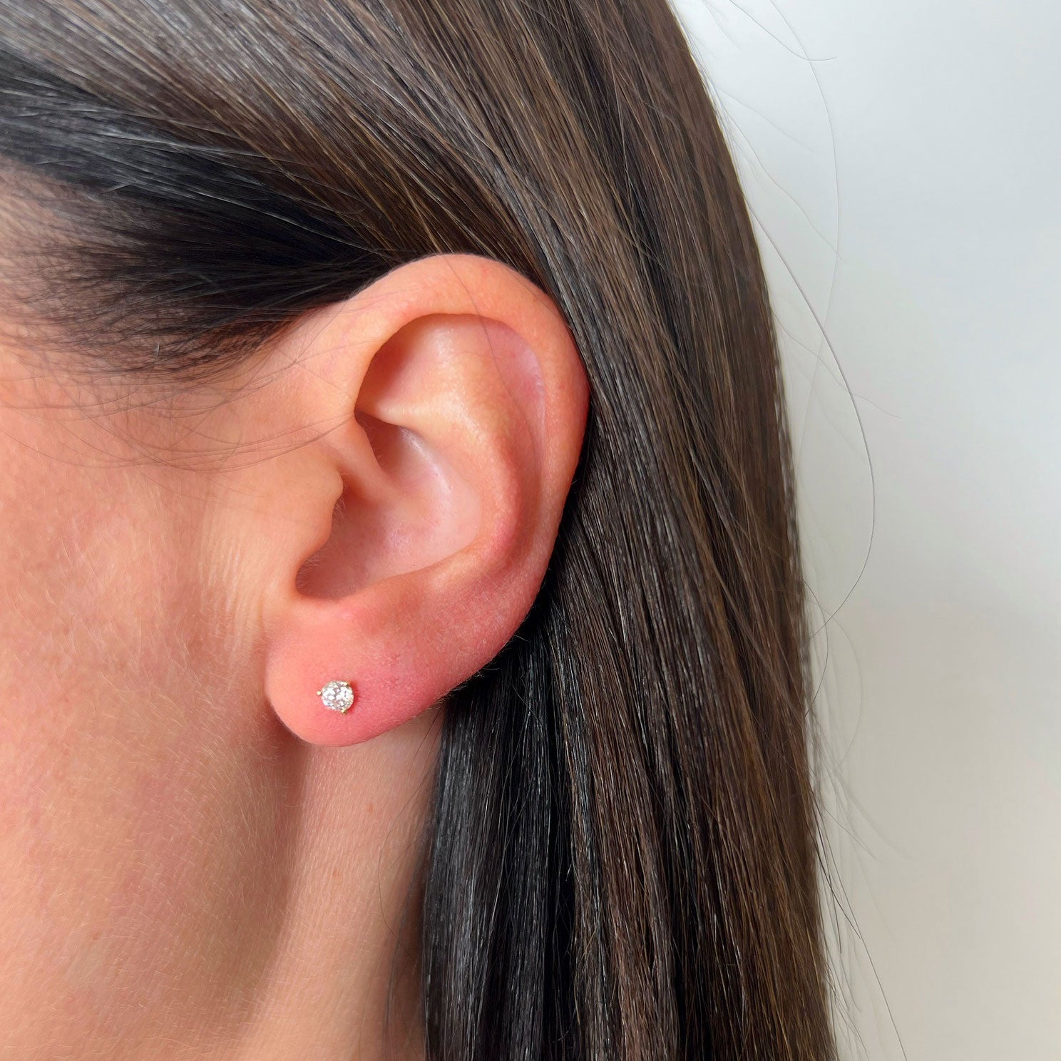 Jumbo Solitaire Diamond Stud Earring in 14k yellow gold styled on ear of model with brown hair