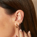 Sasha Hoop Earrings in 14k yellow gold styled on ear of model with brown hair