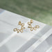 Multi White Quartz Pear Stud Earrings in 14k yellow gold sitting on top of white table