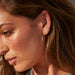 Double Treasure Stud Earring in 14k yellow gold styled on second earring hole on earlobe of model wearing gold hoops