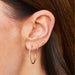 Mini Hummingbird Stud Earring With Diamond Eye in 14k yellow gold styled on third earring hole on earlobe of model wearing hoop earrings and stud earring