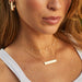 Nameplate Necklace in 14k yellow gold styled on neck of model wearing diamond necklace and 14k yellow gold hoop earrings