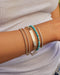 Nameplate Jumbo Link Bracelet in 14k yellow gold styled on wrist of model with turquoise beaded bracelet, two diamond bracelet,s and one gold ball bracelet with model wearing white tshirt