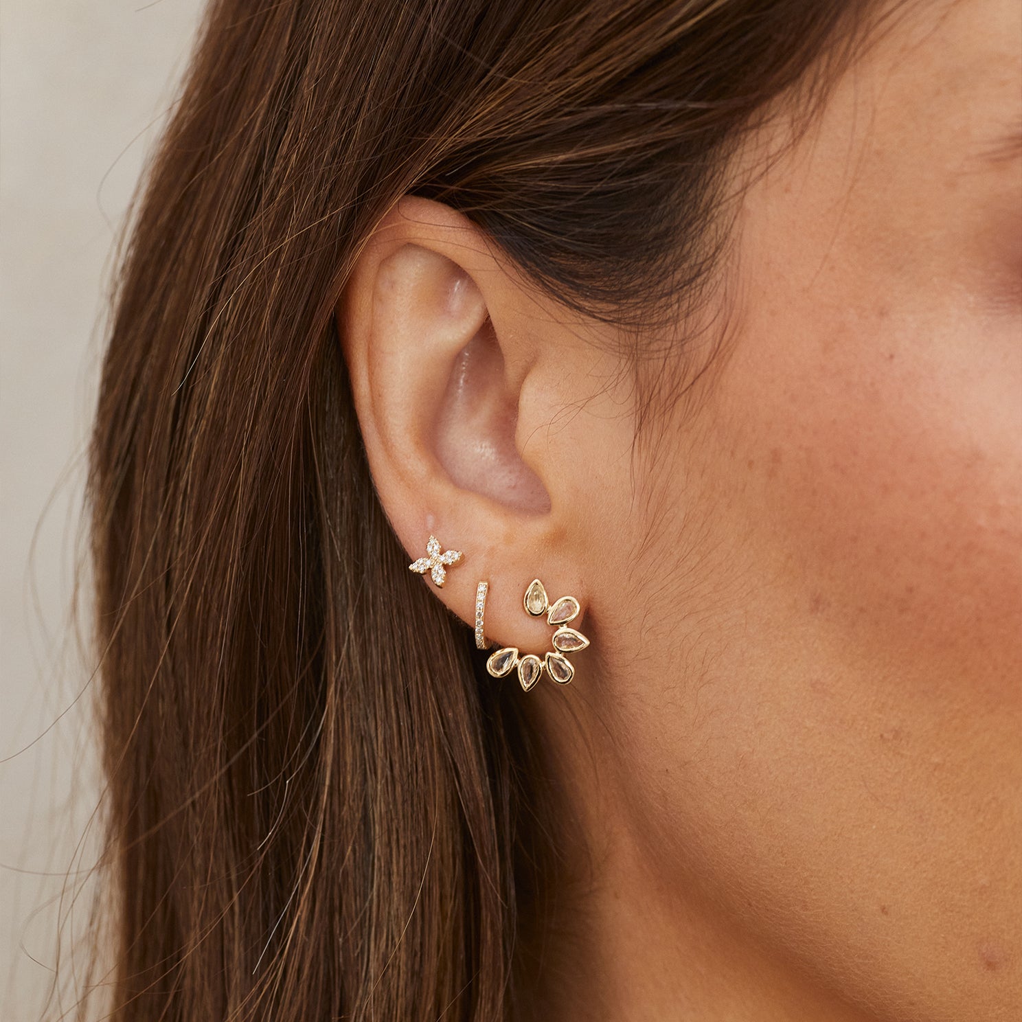 Diamond Blossom Stud Earring in 14k yellow gold styled on ear of model next to huggie and white quartz earring