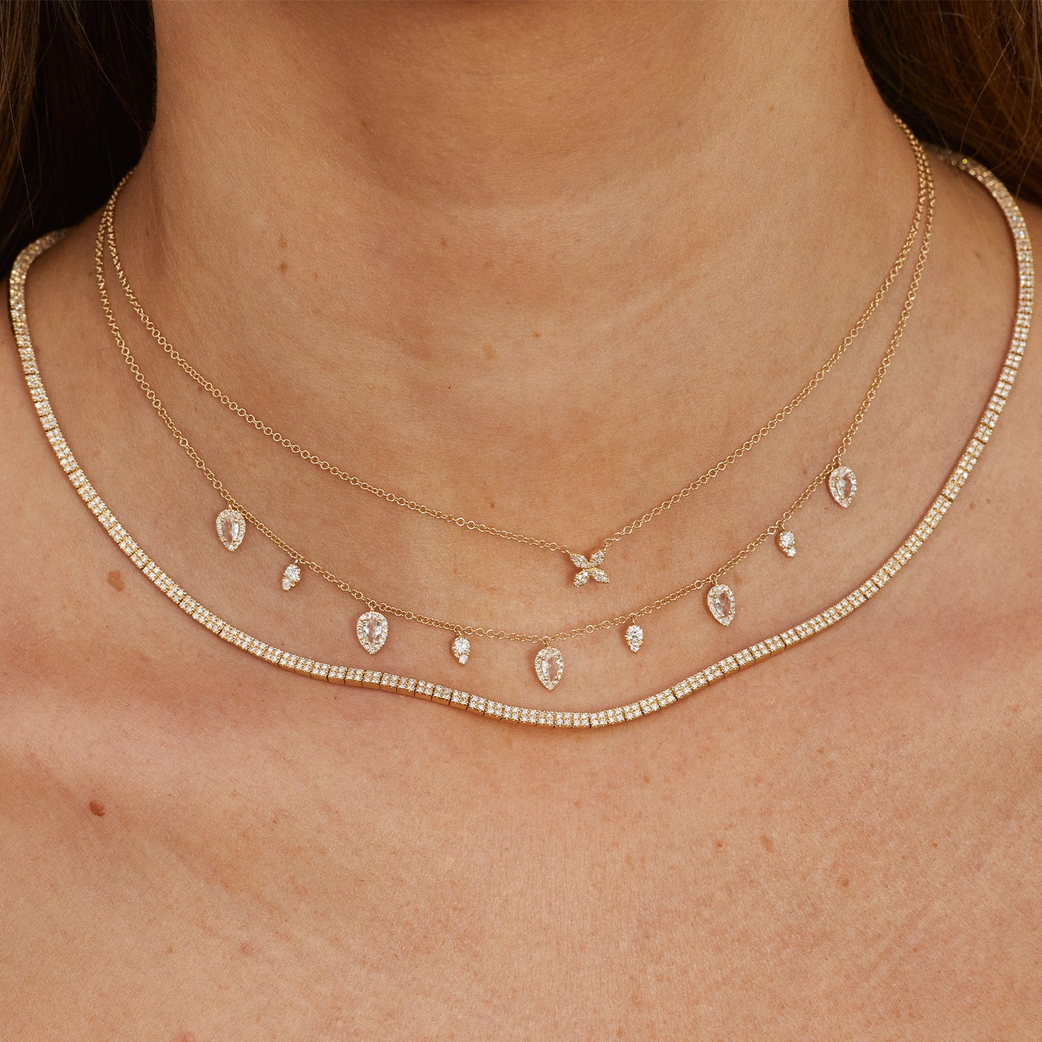Diamond Blossom Necklace in 14k yellow gold styled on neck of model with 5 teardrop necklace and diamond segment necklace