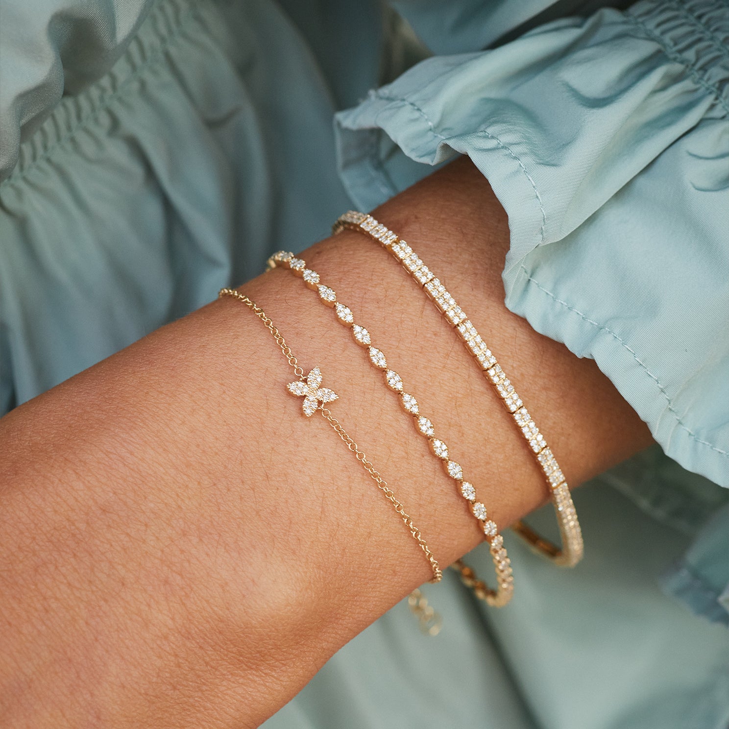 Diamond Blossom Chain Bracelet in 14k yellow gold styled on wrist of model with two diamond bracelets