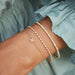 Diamond Blossom Chain Bracelet in 14k yellow gold styled on wrist of model with two diamond bracelets