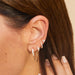 Diamond & Gold Hoop Earrings in 14k yellow gold styled on first earring hole of model with three diamond earrings up ear