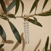 Diamond & Graduated Pearl Drop Earrings in 14k yellow gold dangling on olive tree branch