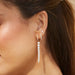 Diamond & Graduated Pearl Drop Earrings in 14k yellow gold styled on first earring hole of model next to pearl huggie earring and pearl stud earring
