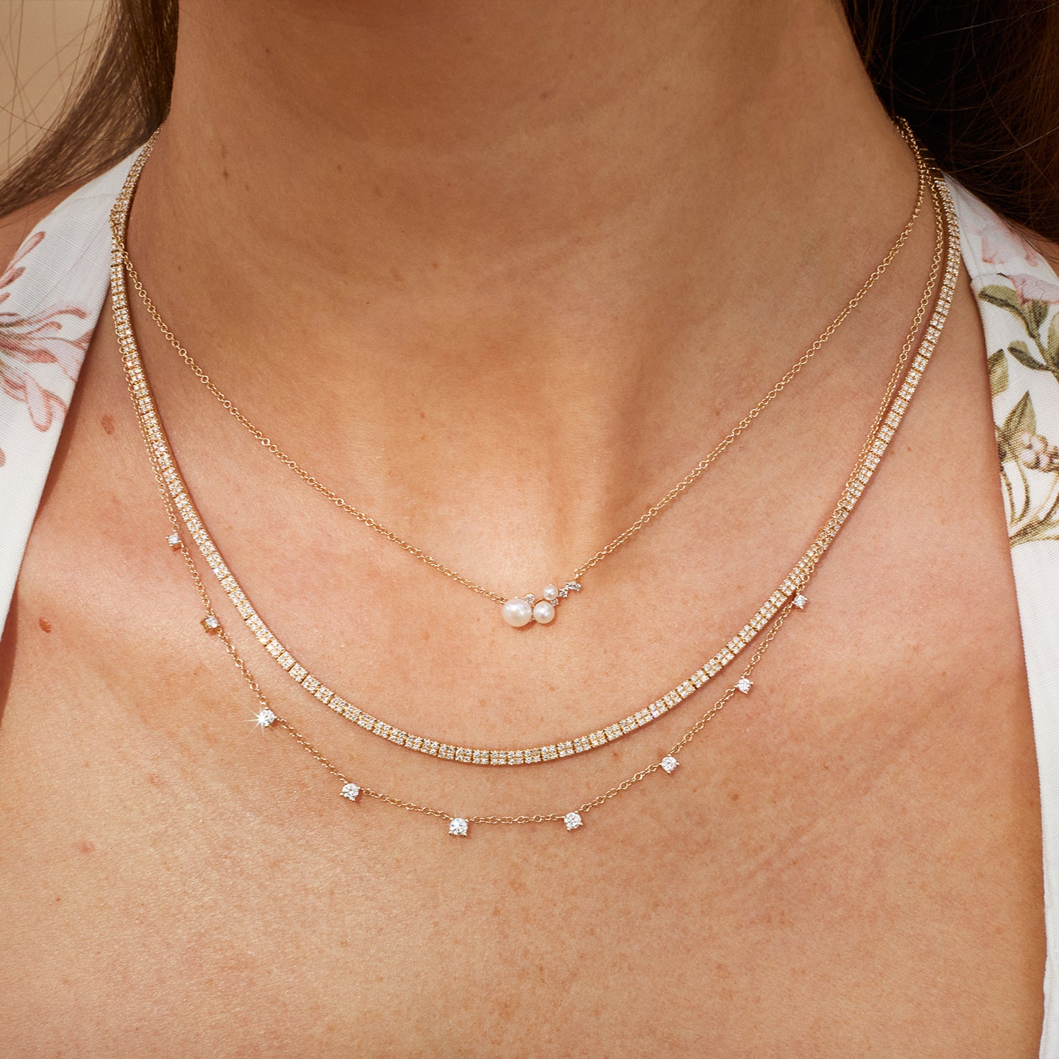 Diamond & Pearl Necklace in 14k yellow gold styled on neck of model with diamond necklaces layered