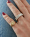 Diamond Hummingbird Signet Ring in 14k yellow gold styled on pinky ring next to emerald cut ring on ring finger both rings styled on fingers of model