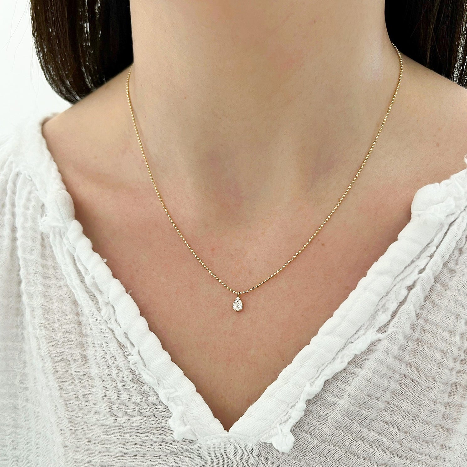 Full Cut Diamond Teardrop Necklace in 14k yellow gold styled on neck of model wearing white blouse