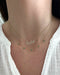 Emerald 5 Teardrop Choker Necklace in 14k yellow gold layered with custom script necklace in Austin both necklaces styled on neck of model wearing white blouse