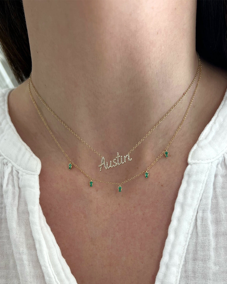 Emerald 5 Teardrop Choker Necklace in 14k yellow gold layered with custom script necklace in Austin both necklaces styled on neck of model wearing white blouse