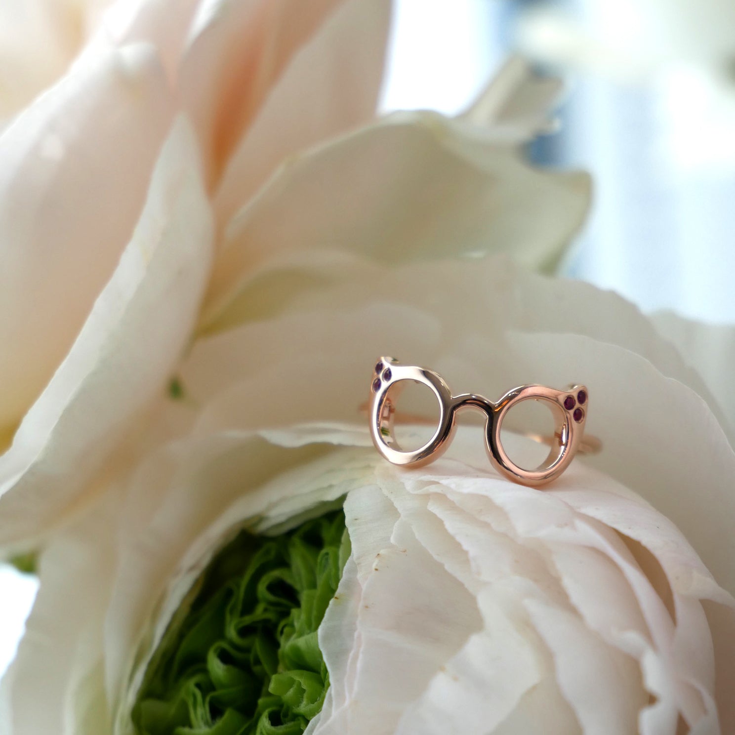 Evan's Sunnies Ring with Rubies in 14k rose gold on top of white flower