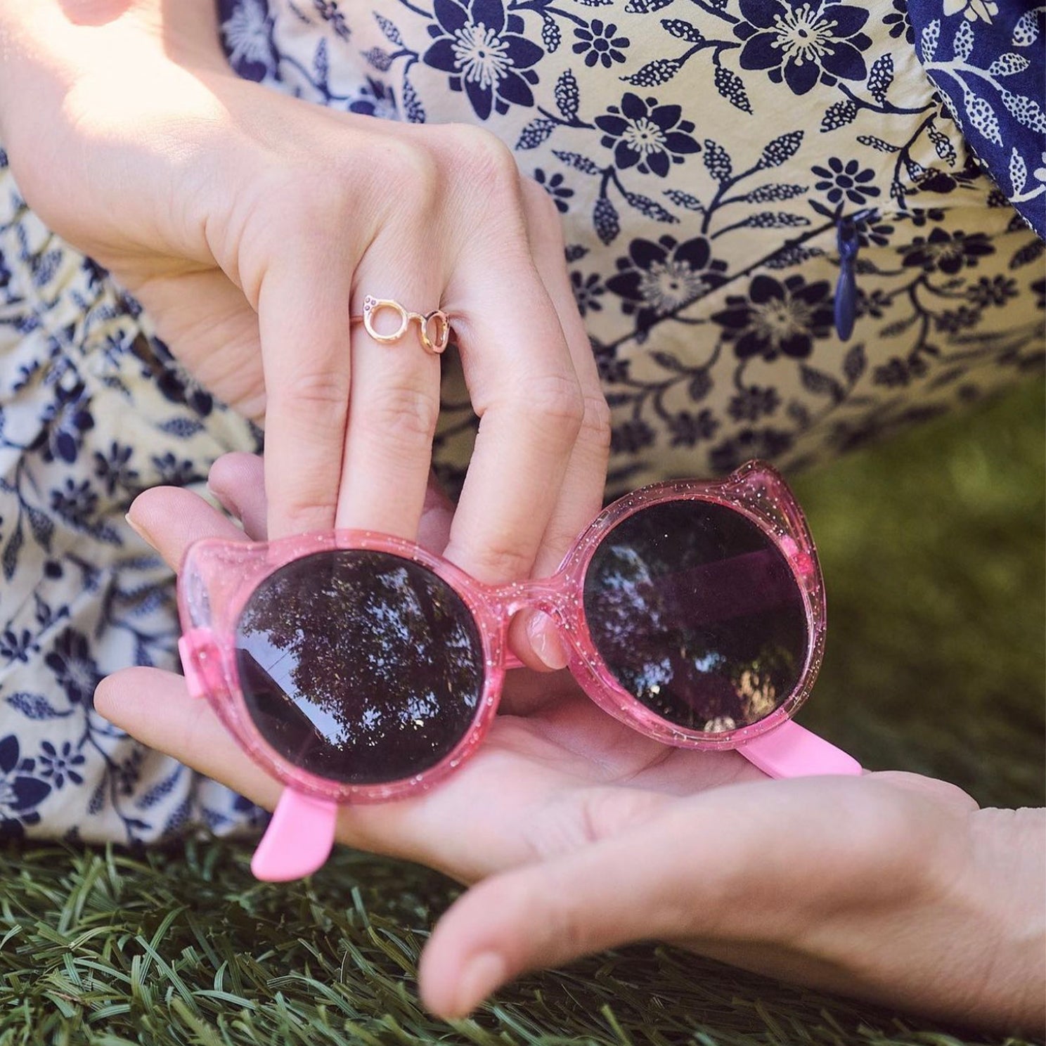 Evan's Sunnies Ring with Rubies in 14k yellow gold styled on ring finger of model holding pink sunglasses