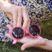 Evan's Sunnies Ring with Rubies in 14k yellow gold styled on ring finger of model holding pink sunglasses