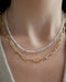 Birthstone Bead Necklace In Aquamarine styled on neck of model with gold jumbo chain necklace and wearing tan sweater