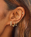 14k yellow gold pillow huggie, bezel shimmy huggie. and diamond bezel drop huggie on ear