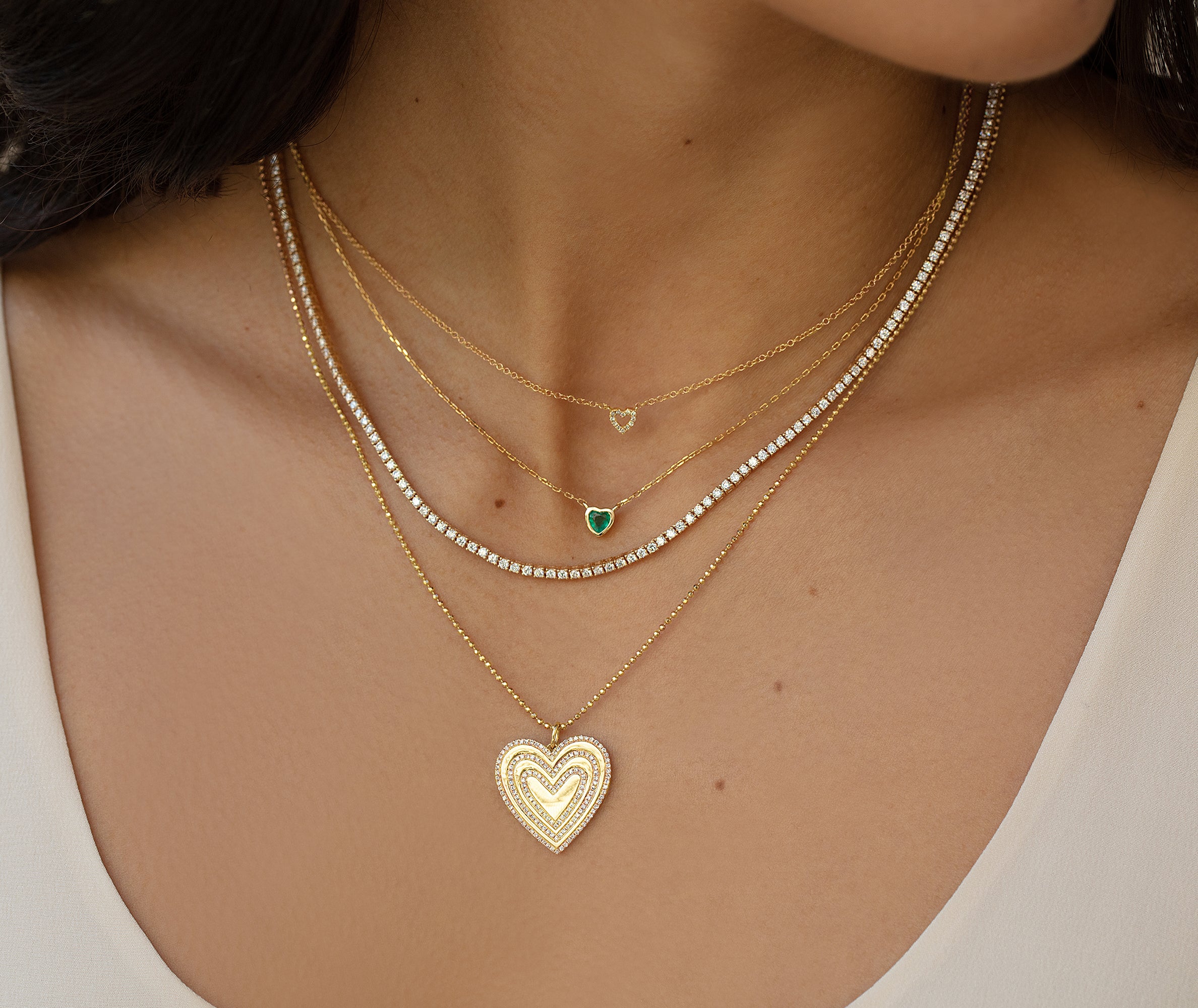14k yellow gold chain necklace with fixed 5.6mm emerald jewel heart pendant styled on model with layered necklaces