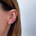Mini Diamond Pear Stud Earring in 14k yellow gold styled on second earring hole on earlobe of model with clover diamond earring in first earring hole