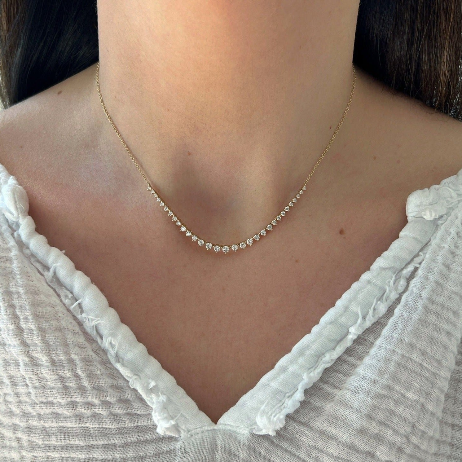 Graduated Diamond Necklace in 14k yellow gold styled on neck of model wearing white blouse