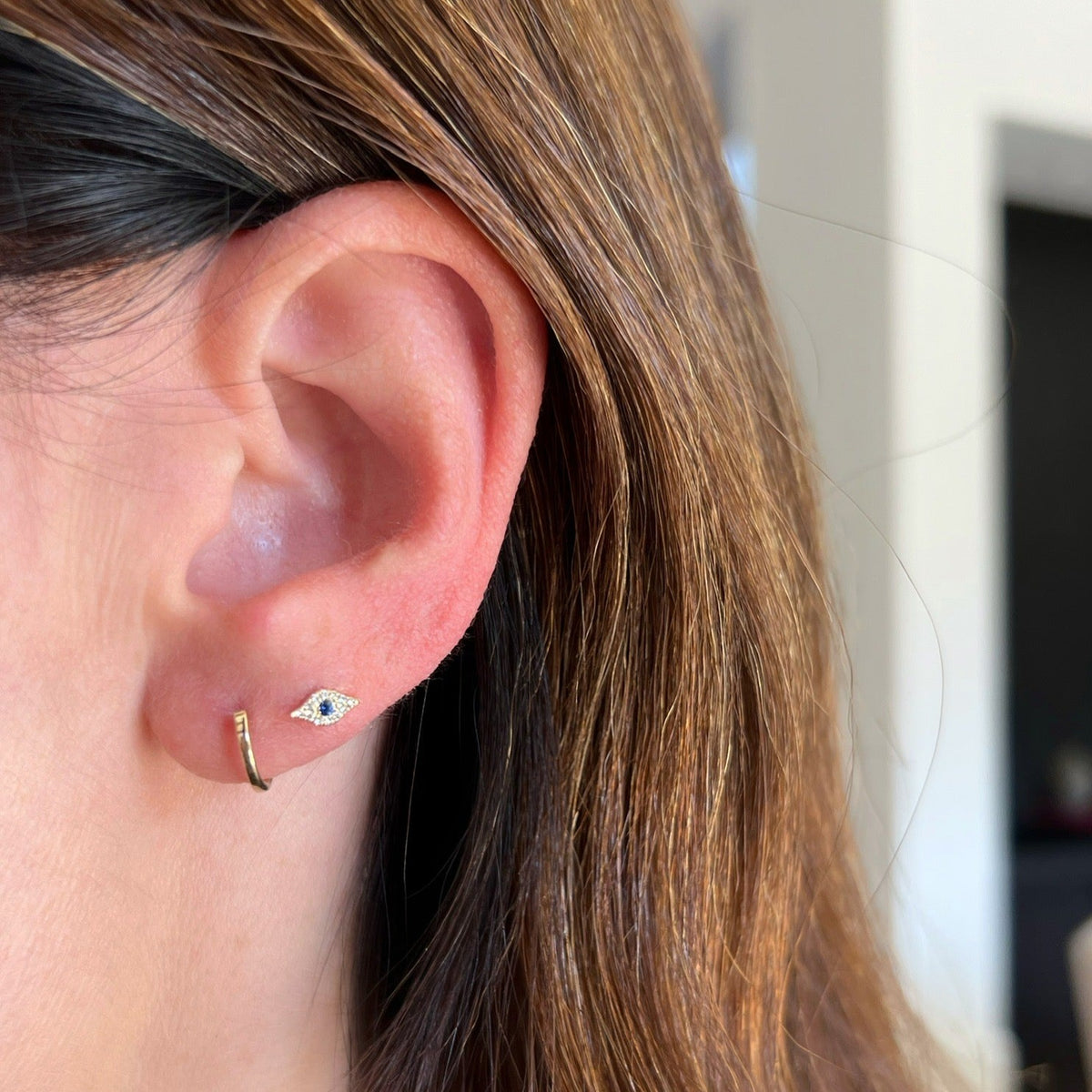 Gold Mini Huggie Earrings in 14k yellow gold styled on ear of model