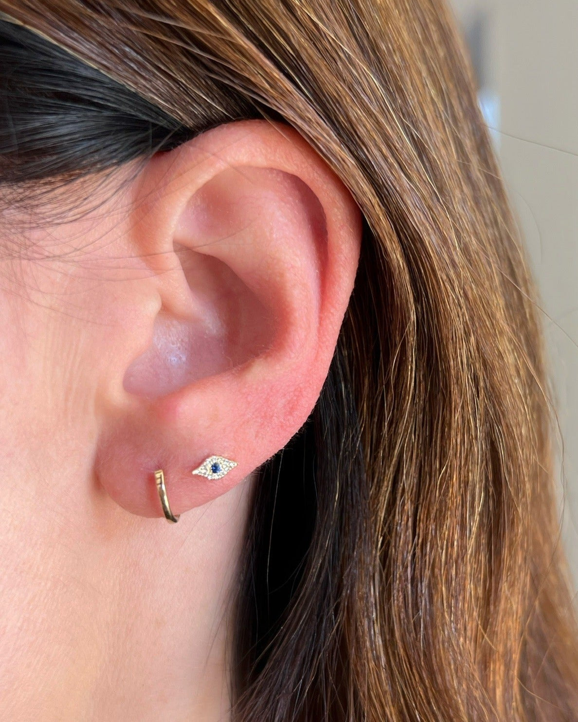 Gold Mini Huggie Earrings in 14k yellow gold styled on ear of model