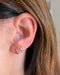Gold Mini Huggie Earrings in 14k yellow gold styled on ear of model