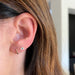 Gold Mini Huggie Earrings in 14k yellow gold styled on ear of model
