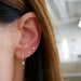 14K Yellow Gold Diamond Mini Huggie with Bezel Drop styled on first earring hole of model