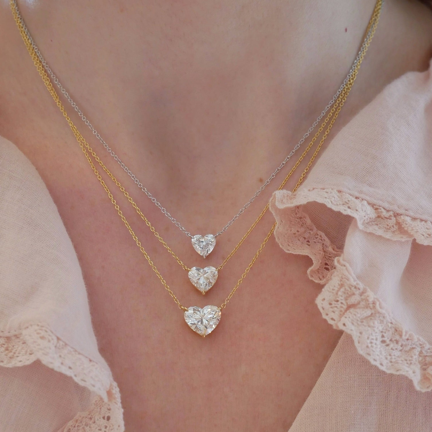 Diamond Heart Solitaire Necklace in 14k white gold with 1.02 carat heart shaped diamond and 18k yellow gold 2.02 carat heart shaped diamond and 18k yellow gold chain with 3.01 heart shape diamond styled on neck of model