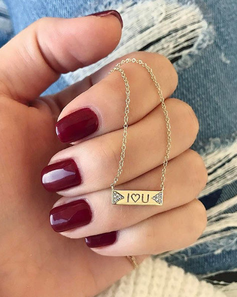 Diamond Double Triangle Mini Nameplate Necklace in 14k yellow gold holding in hand of model