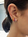 Diamond Orange Enamel Huggie Earring in 14k yellow gold styled on ear lobe of model next to berry enamel huggie, pink enamel huggie, and rainbow huggie