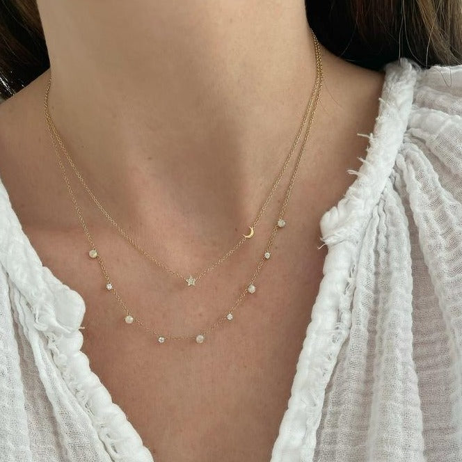 Baby Diamond Star And Gold Moon Necklace in 14k yellow gold styled with diamond burst necklace styled on neck of model