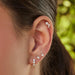 Diamond & Pearl Ear Climber in 14k yellow gold styled on cartridge piercing on ear of model with two pearl stud earrings and one jumbo diamond huggie 