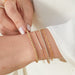 Diamond Grace Bracelet styled on wrist of model with gold ball bracelet, chain bracelet, and diamond bar bracelet