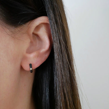 Diamond Black Enamel Huggie Earring in 14k yellow gold styled on ear lobe of model