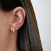 Diamond Light Pink Enamel Huggie Earring in 14k yellow gold styled on ear lobe of model next to diamond and gold cherry stud earring
