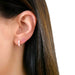Diamond Blush Enamel Huggie Earring in 14k yellow gold next to pink sapphire baguette stud earring styled on ear lobe of model