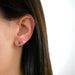 Diamond Hunter Green Enamel Huggie Earring in 14k yellow gold styled on ear of model next to evil eye stud earring