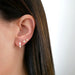 Diamond Double Star Stud Earring in 14k yellow gold styled on ear lobe next to white enamel huggie earring