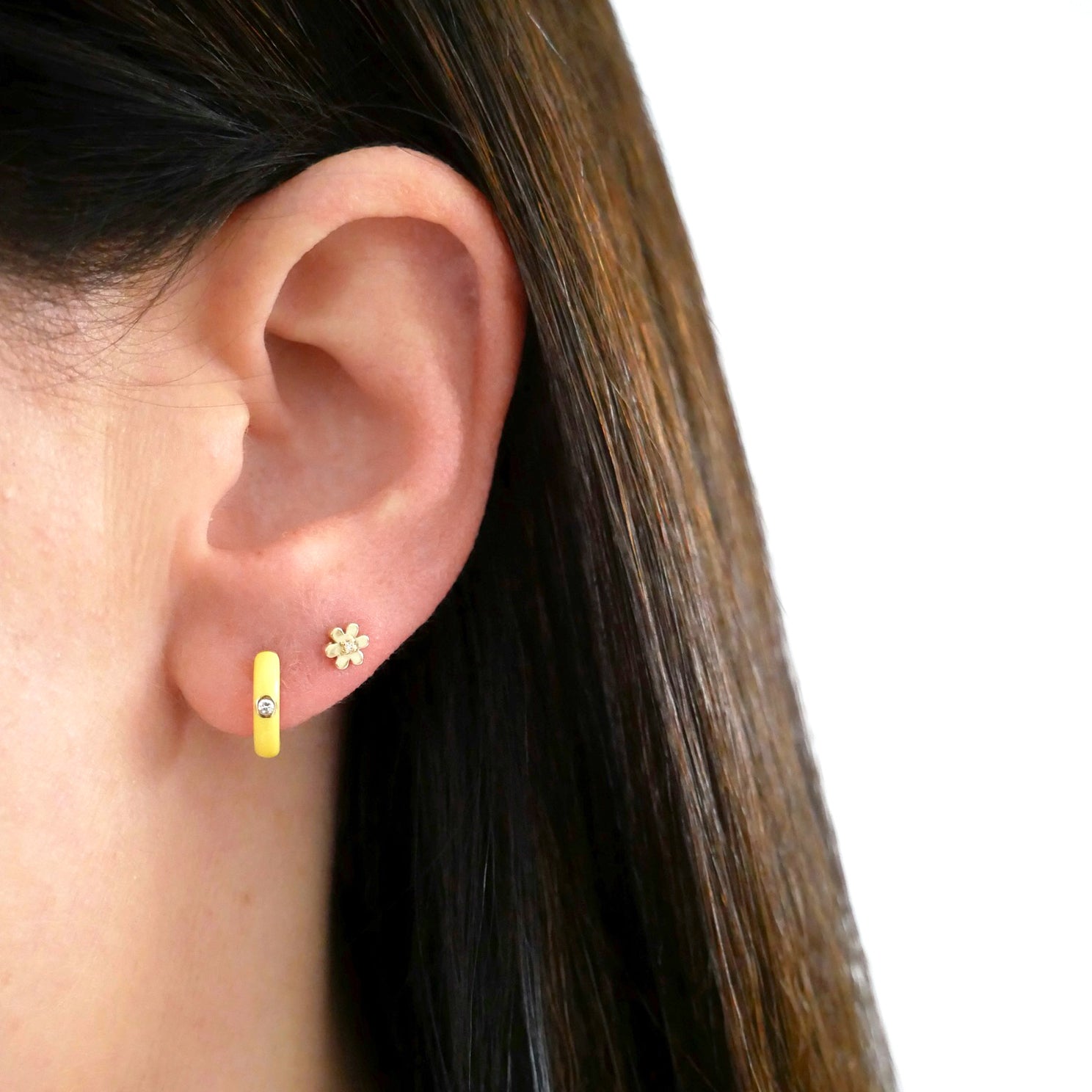 Diamond Yellow Enamel Huggie Earring in 14k yellow gold next to flower stud styled on ear of model