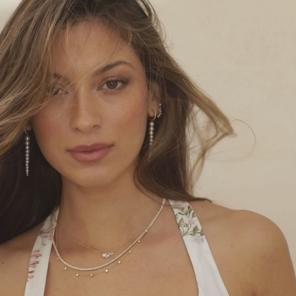 Diamond & Pearl Necklace in 14k yellow gold styled on neck of model with diamond necklaces layered and model pushing hair back with no audio