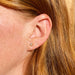 Baby Solitaire Diamond Stud Earring in 14k yellow gold on second earring hole of earlobe of model with red hair