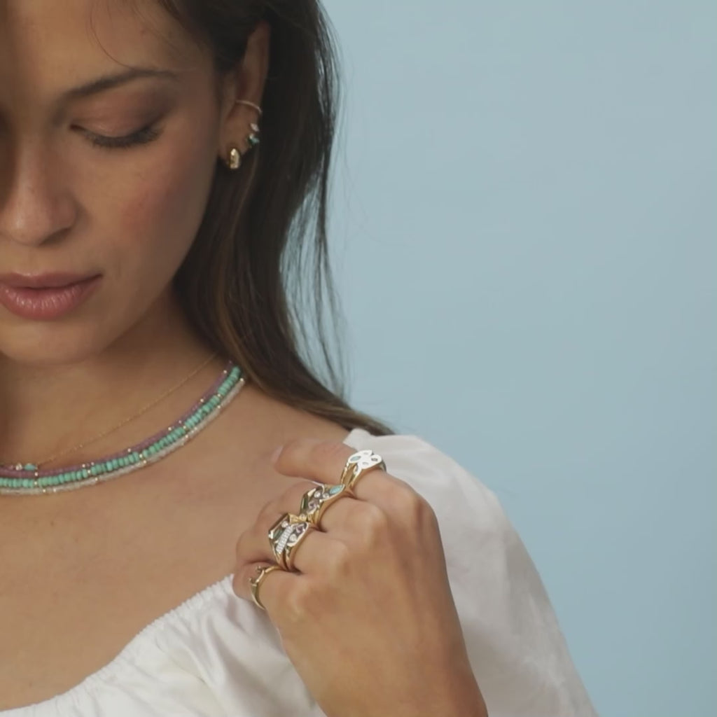 Treasure Bar Necklace styled on neck of model wearing three beaded necklaces and ten gold rings with no audio