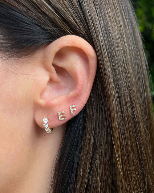Diamond Initial Stud Earring in 14k yellow gold initial E and F styled on ear of model next to diamond huggie earring