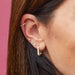 Diamond Mini Arrow Stud Earring in 14k yellow gold styled on ear lobe of model next to heart stud earring and jumbo lola hoop earring of model