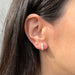 Gold Mini Ball Stud Earring in 14k yellow gold styled on second earring hole on ear lobe of model with brown hair